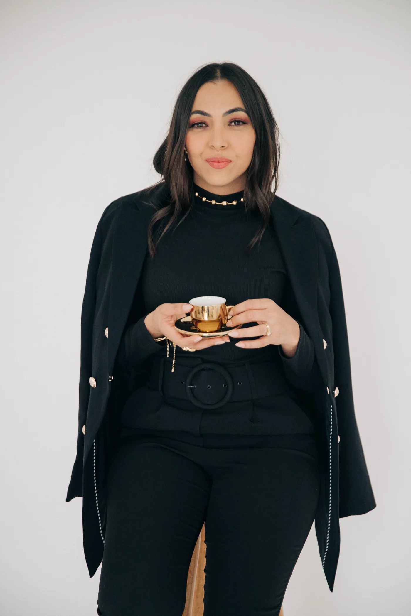 Mari Ferreira de casaco preto, segurando uma xícara
